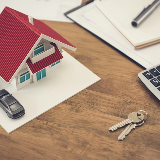 red miniature house beside keys and calculator